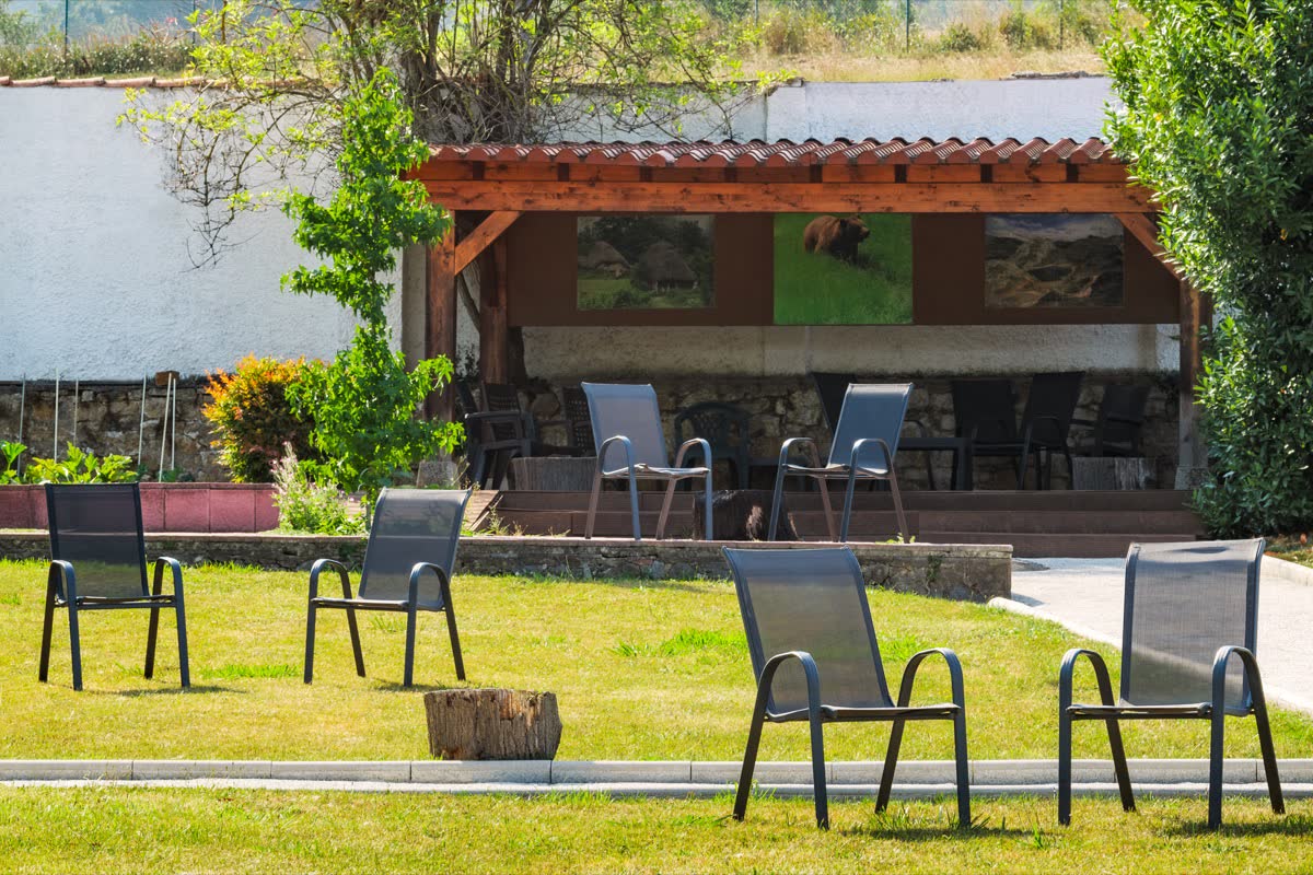 Pérgola de madera con sillas, abierta a la pradera del jardín